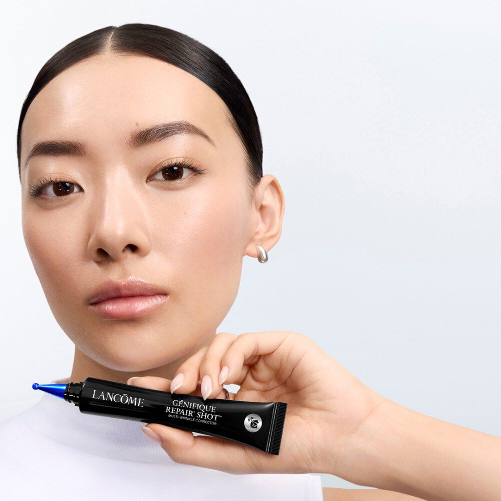 Model shot holding the Genifique Repair Shot close to her chin.