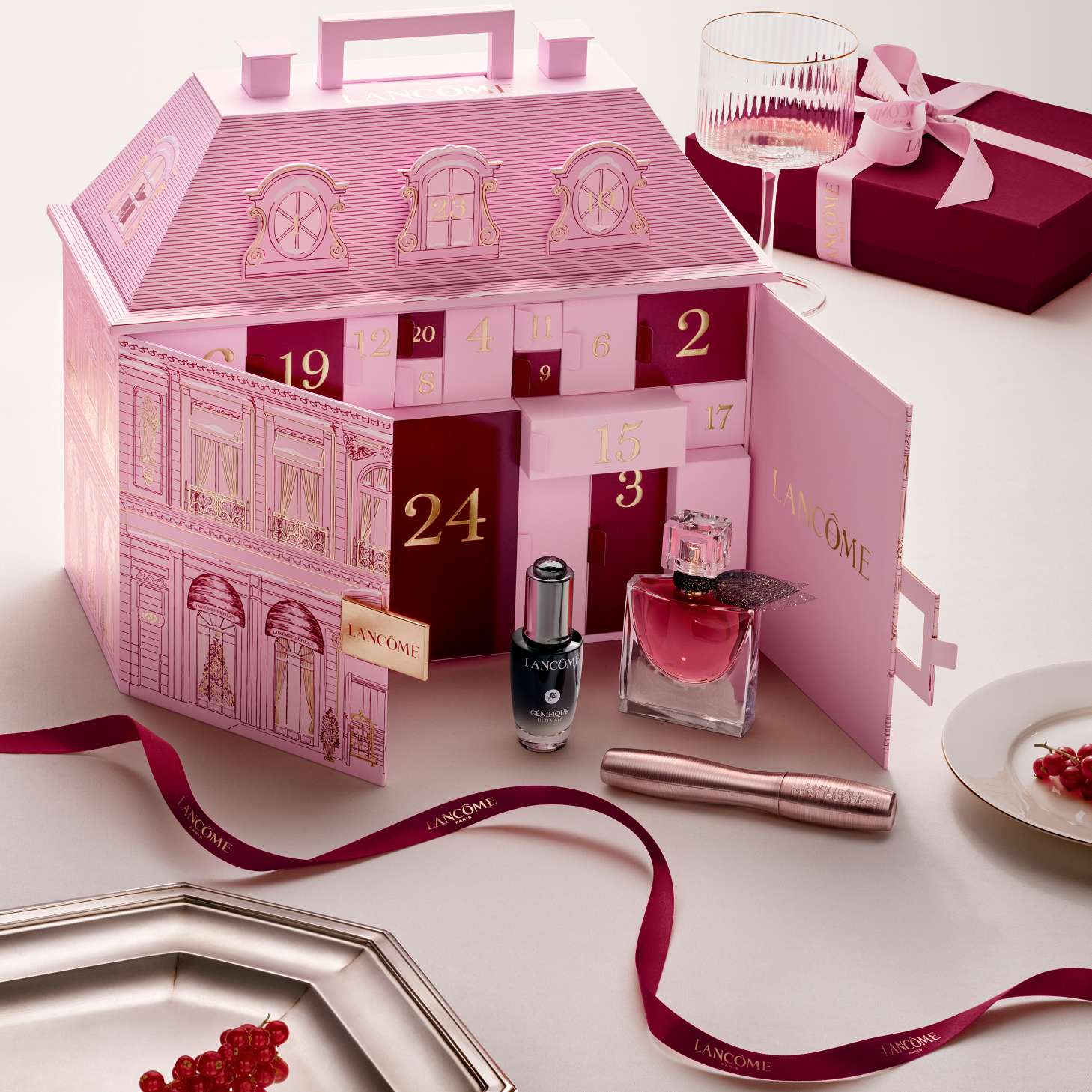 An open pink Lancome townhouse advent calendar displayed with beauty products and a red ribbon.